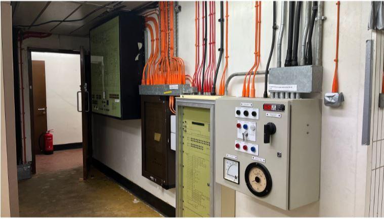 A corridor with panels of machinery and brightly coloured wires.