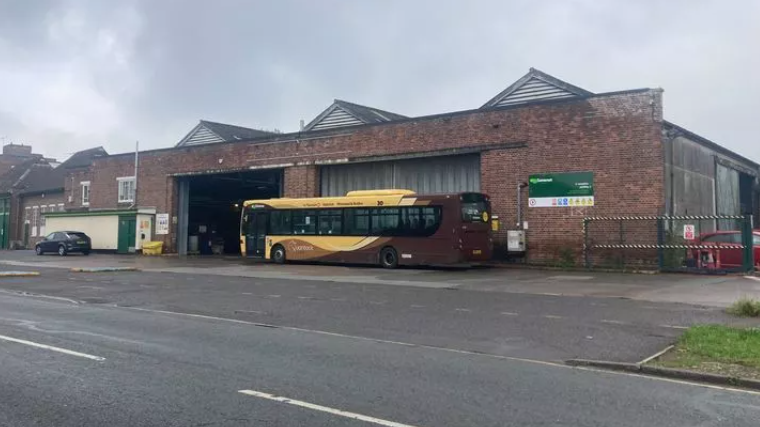 A tired looking depot with a brown and yellow bus parked outside