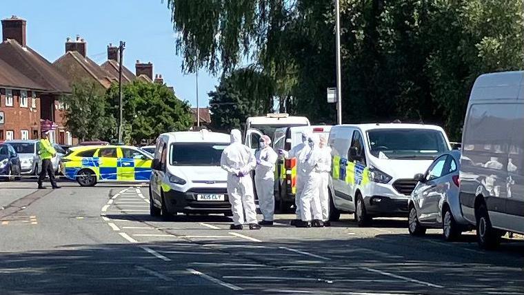 Police in Farley Hill, Luton, with five of them wearing hazmat suits, alongside a number of police vehicles