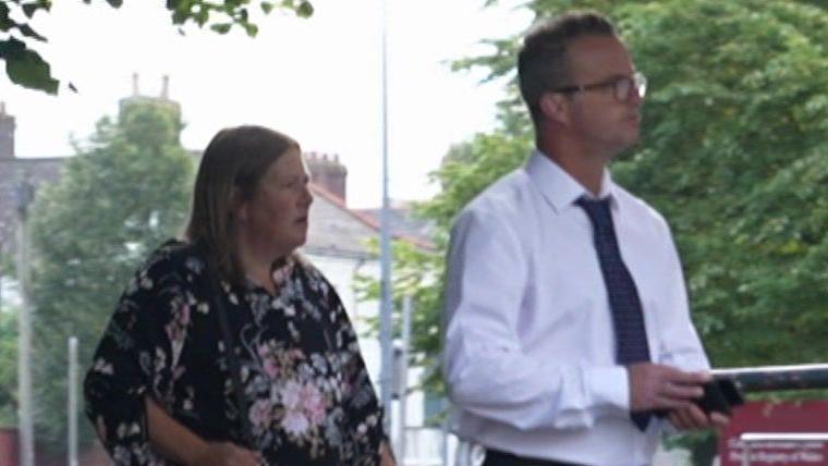 Rebekah Edwards, in a blouse patterned with flowers, and Mark Edwards, in spectacles, white shirt and dark tie, arrive at court