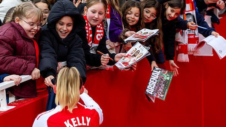 Arsenal fans stretch over the side of the Emirates tunnel to reach Chloe Kelly in a bid to secure an autograph