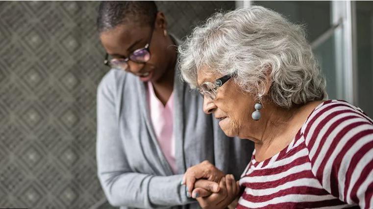 A woman helping an elderly lady down the stairs