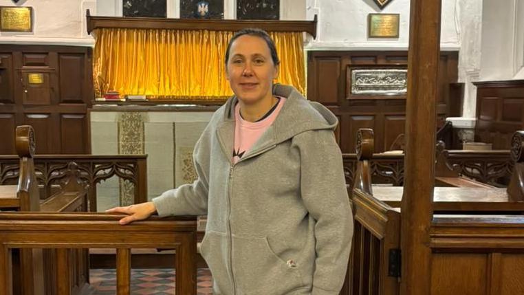 Nikki Dilorenzo, a woman wearing a tracksuit standing inside a church