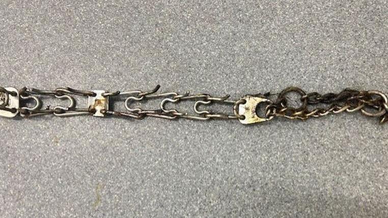 A stained barbed metal chain on a grey background.