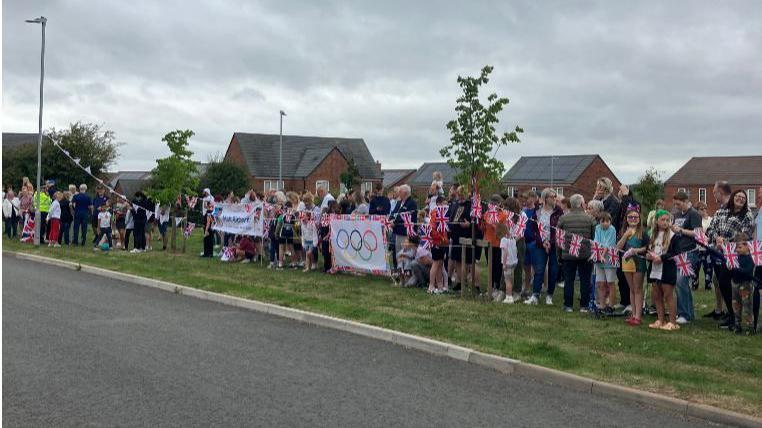 Wide shot of a large group of people holding banners and bunting