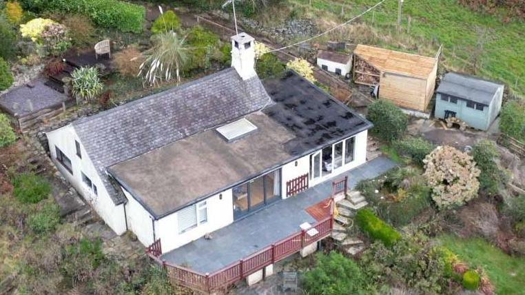 A drone shot of the villa surrounded by trees and grass