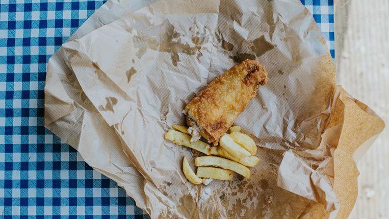 Photo of half-eaten fish and chips on a blue and white table cloth