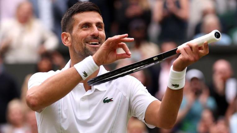 Novak Djokovic makes a violin gesture to the crowd at Wimbledon