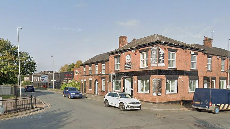 A traffic lights junction on Oldham Road, Middleton, Rochdale, Greater Manchester, on a sunny day.