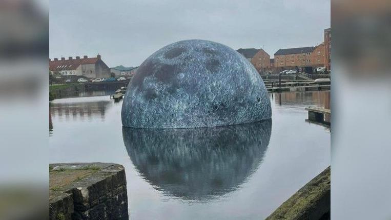 The giant moon sculpture lying partially-submerged in Bridgwater Docks