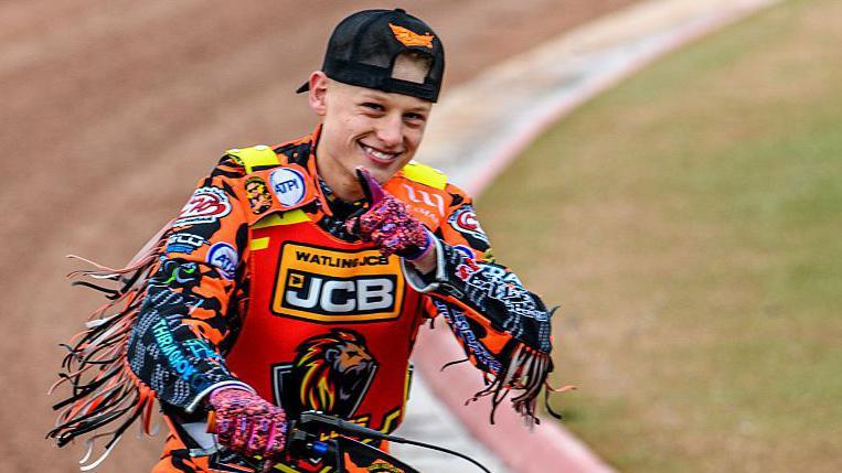 Cooper Rushen points to a camera after a race