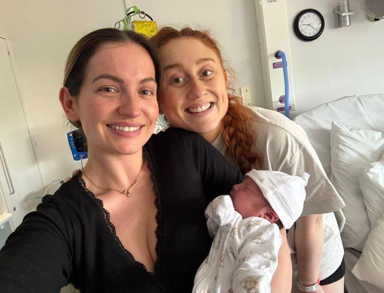 Georgia holding a newborn baby and Daisy 