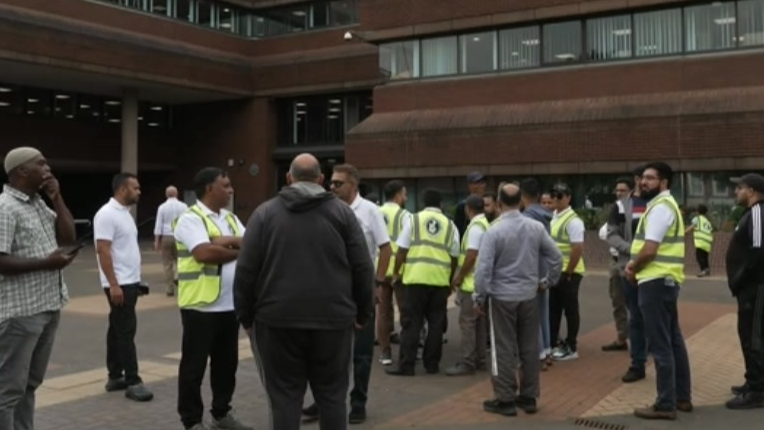 About 20 private hire drivers stand outside council offices in Wolverhampton, some in reflective bibs