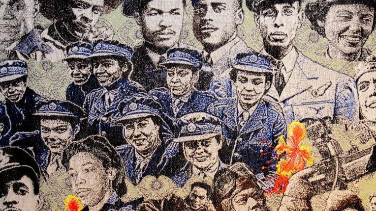 Image of the tapestry, with blue, cream and yellow stitching with faces of Wolrd War 2 veterans looking out to the viewer.