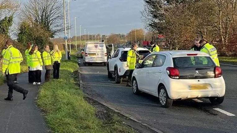 Police officers conducting roadside checks for drug and drink driving on the A59 at Robin Island on vehicles. Three vehicles are pulled into a layby with several officers in hi vis jackets stood close by.