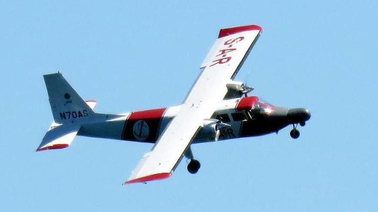 A red and white plane used by the Channel Islands Air Search team flying on a sunny and cloud free day over the Channel Islands.