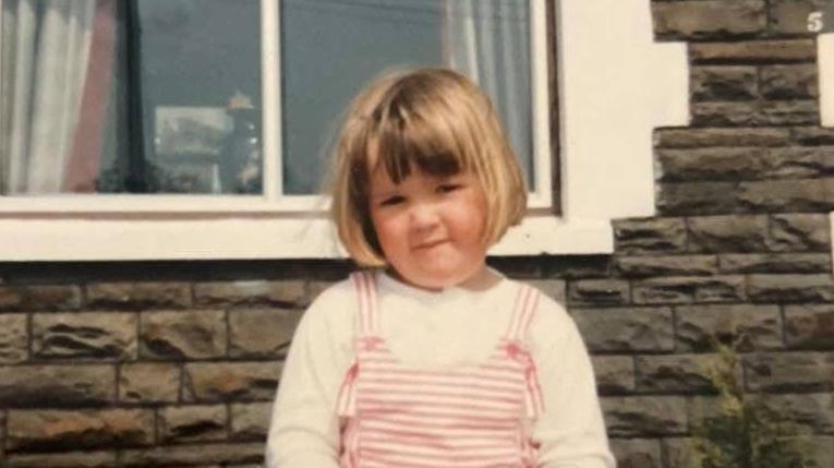Lois Roberts yn ifanc o flaen tŷ teras