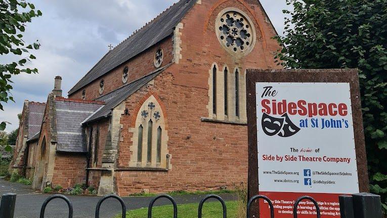 The former St John's Church from the side with a sign outside that says The SideSpace at St John's