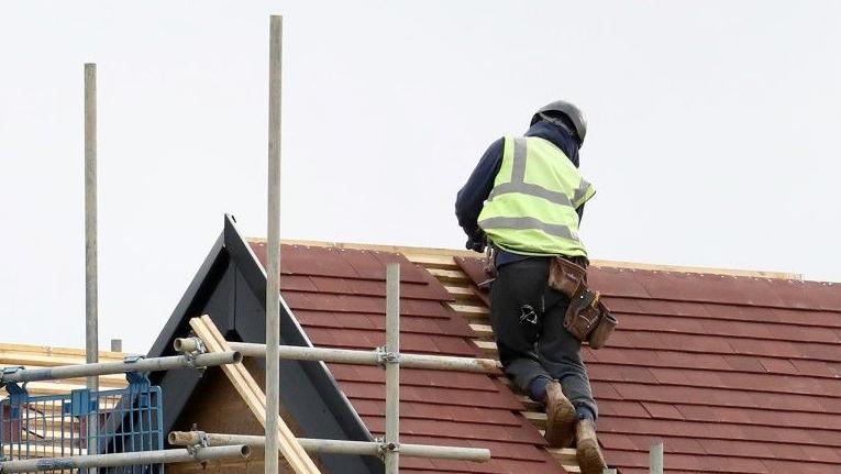 Construction worker fixes roof tiles