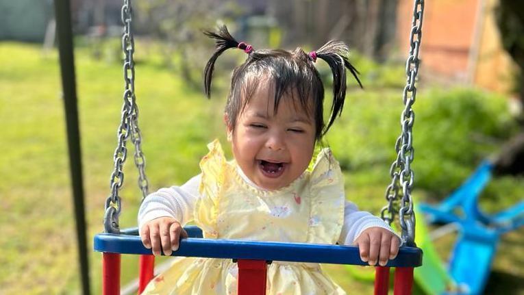 Symayyah playing on a set of swings