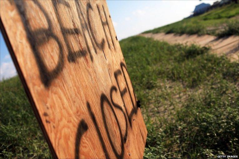 A sign announces a closed beach due to the oil spill