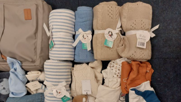 Items of baby clothing are rolled up with store labels attached