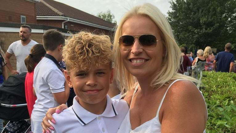 A young Mikey Roynon and his mum who has her arm around him, and they are smiling