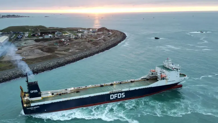 A large blue DFDS ferry pulls out of Jersey's harbour.