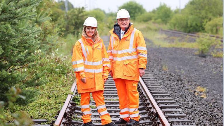 Labour's North East mayor Kim McGuinness and deputy mayor Martin Gannon wearing high visibility clothing on a railway line.