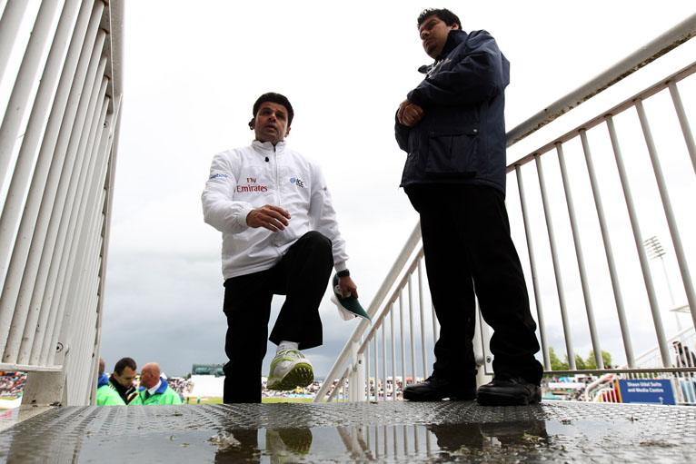 Umpire Alim Da leaves the field after one of numerous pitch inspections on a rain-disrupted day at the Rose Bowl