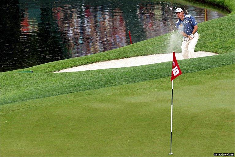 Lee Westwood plays a bunker shot on 18