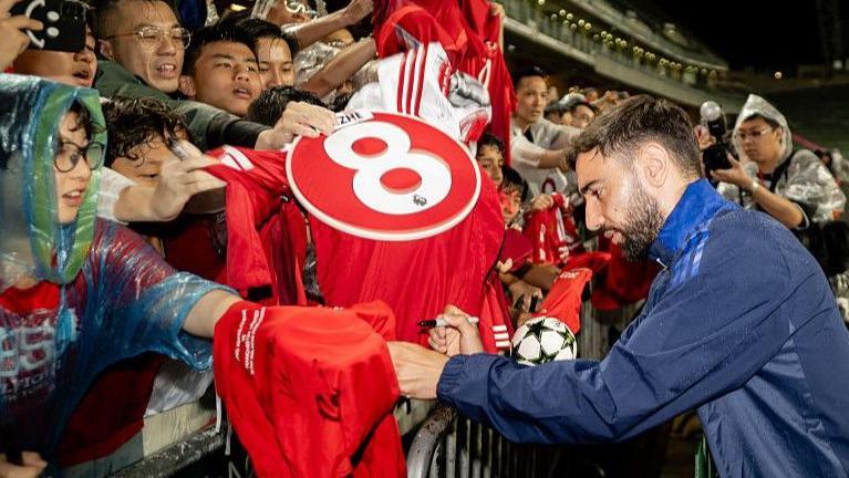 Manchester United skipper Bruno Fernandes signs a shirt for a fan during a training session in Hong Kong