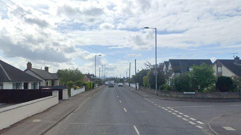 A Google Street View image of a residential road. There are two cars in the distances and a number of homes on either side of the street.