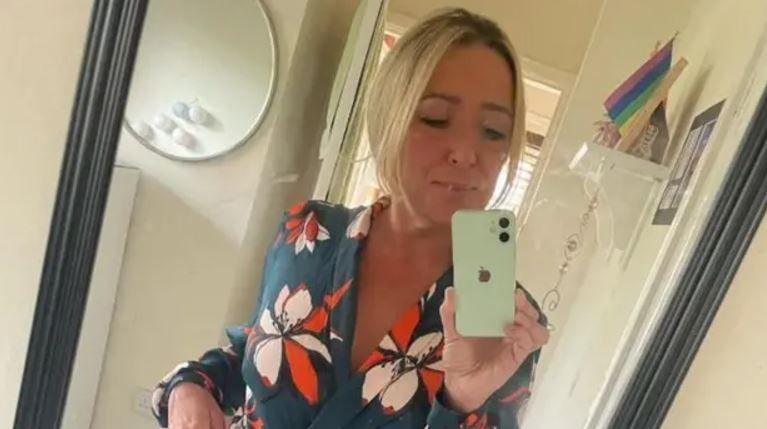 Teresa McMahon taking a selfie, wearing a black top with peach and orange flowers. Her blonde hair is tied back in a pony tail.