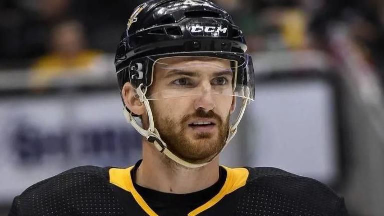 Adam Johnson wearing a black and yellow jersey and a black helmet with a visor.