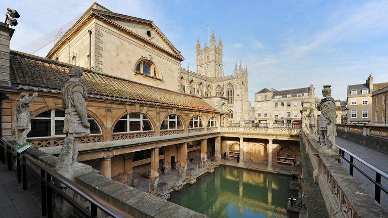 The Great Bath seen from the Terrace at the Roman Baths, with Bath Abbey in the background, in Bath, Somerset.