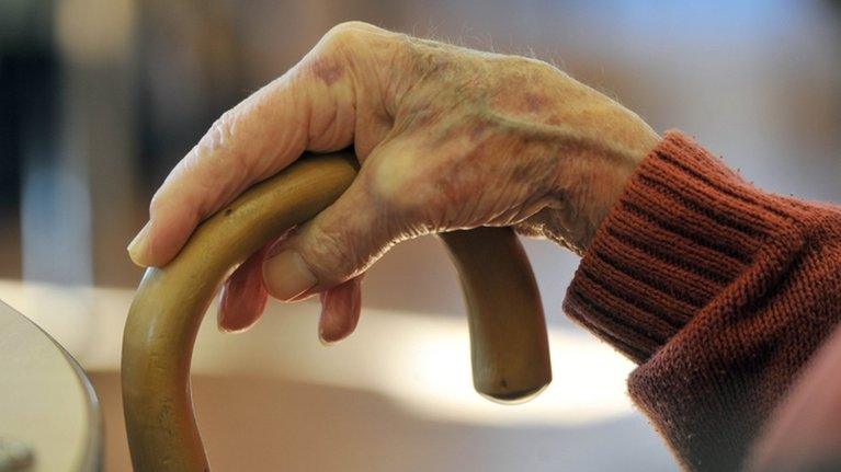 Elderly lady's hand on walking stick