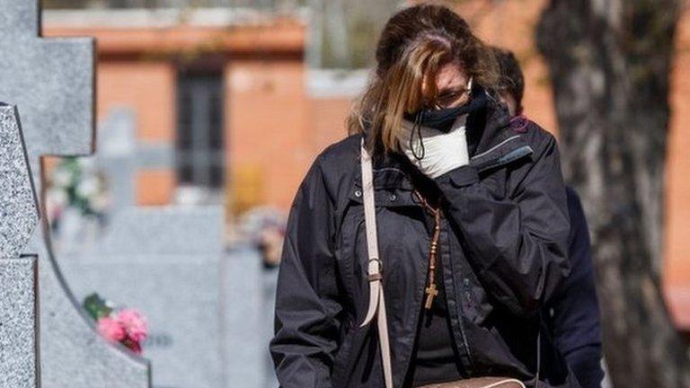 A woman arrives for the burial of a COVID-19 coronavirus victim at the Fuencarral cemetery in Madrid