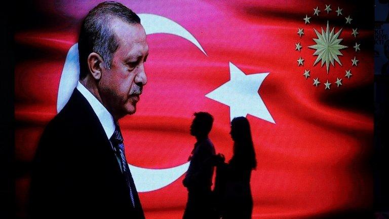 People walk past an election poster for Turkey's President Tayyip Erdogan in Istanbul on 14 June, 2018.