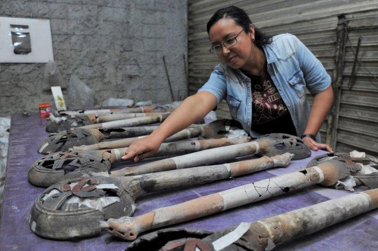 An archaeologist shows incense burners, part of an altar unearthed by archaeologists at a plot near Plaza Garibaldi in downtown Mexico City, in this photo distributed to Reuters by the National Institute of Anthropology and History on November 30, 2021.