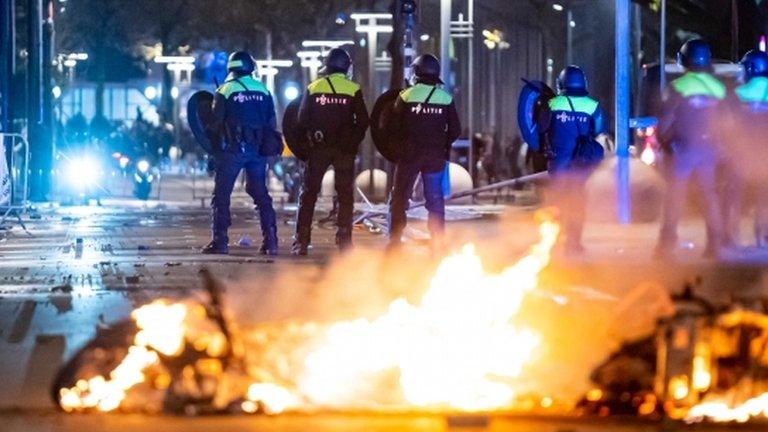 Policemen stand near burning objects