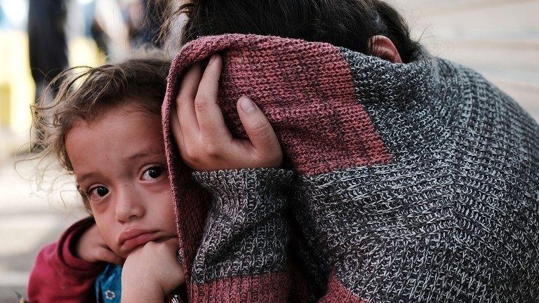 A Honduran child and her mother, fleeing poverty and violence in their home country, waits along the border bridge after being denied entry from Mexico into the U.S