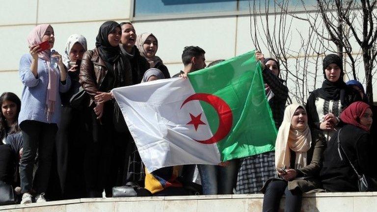 Algerian protesters hold up a national flag