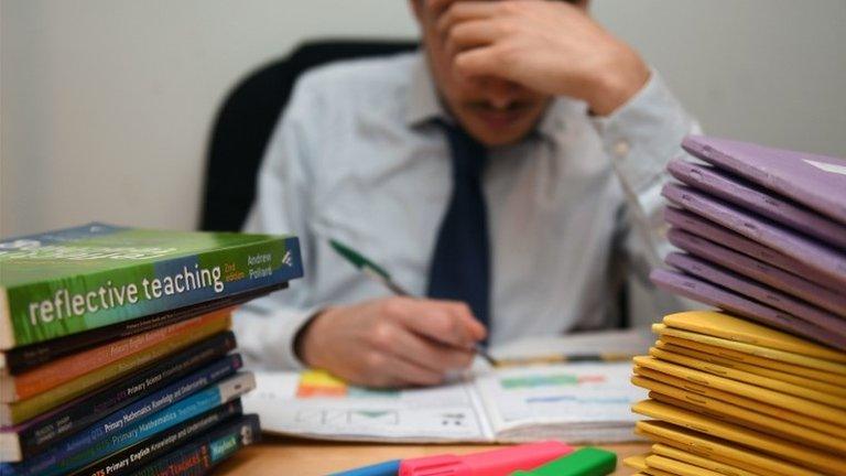 teacher at desk with head in hands