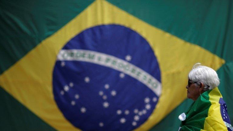 A woman is seen with a Brazilian flag in front of the National Congress during a protest against corruption, in Brasilia, Brazil March 26, 2017