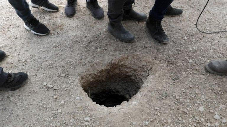 Police officers and journalists gather around the exit of a tunnel allegedly used to escape from Gilboa Prison, northern Israel (6 September 2021)