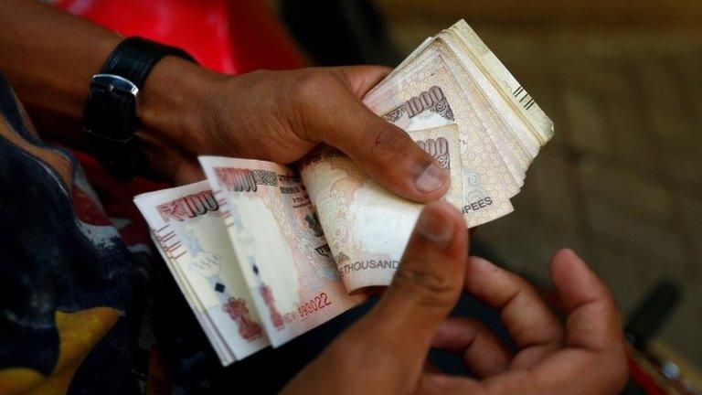 A man counts 500 and 1000 Indian rupee banknotes outside a branch of Bank of India in Mumbai, India, November 10, 2016