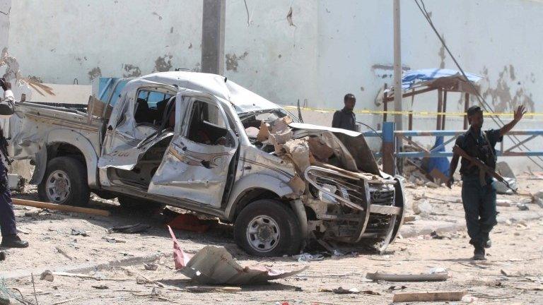 A policeman gives instructions near the wreckage of a car destroyed during a suicide bombing near the African Union"s main peacekeeping base in Mogadishu, Somalia, July 26, 2016