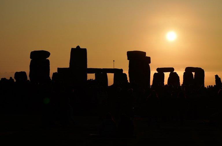 The Sun rises behind the entrance to the stone circle