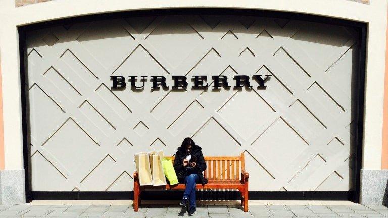 A women sits in front of a Burberry shop